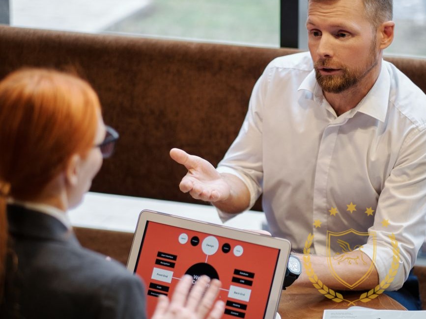 Two people discussing material on a laptop during an indoor meeting.