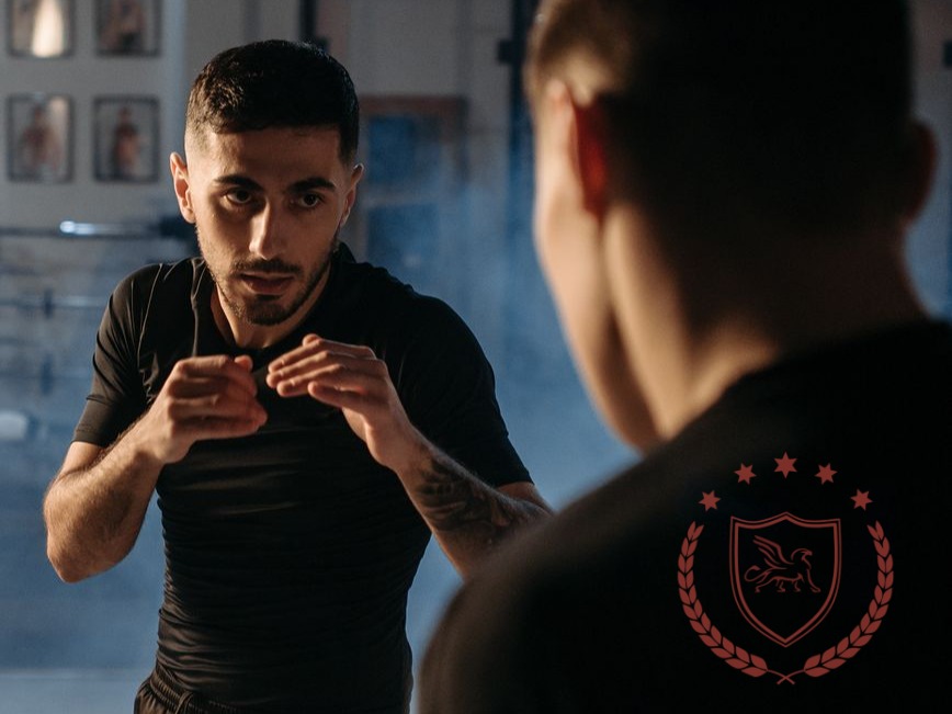 Two people practising close-range defensive movements indoors.