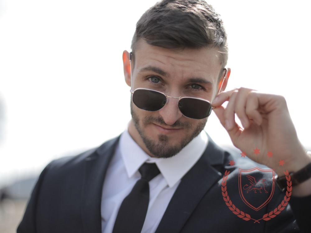 A man in a suit adjusting his sunglasses.